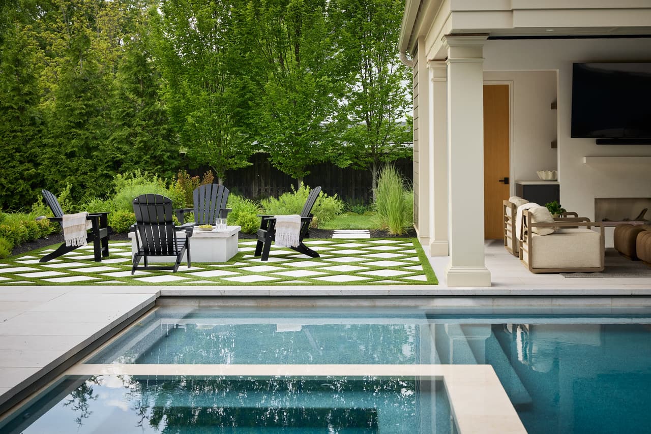 Custom New Jersey backyard with swimming pool covered pavilion outdoor fireplace fire pit seating and landscaped stone terrace in a indoor and outdoor living project in Westfield, NJ