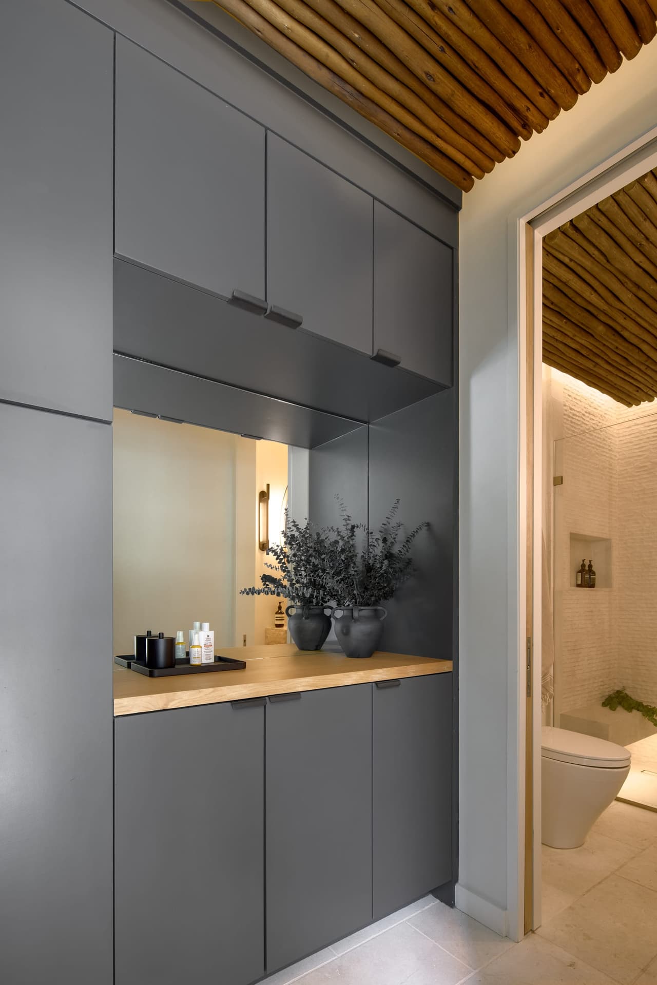 Charcoal cabinetry and built-in storage beside the pool bathroom inside a Westfield, NJ backyard pavilion, under a reeded ceiling