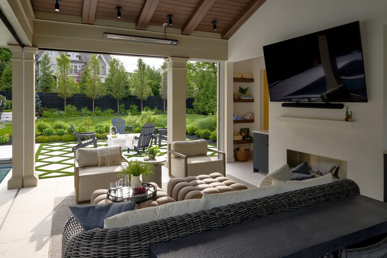 Custom covered outdoor living room with vaulted wood ceiling fireplace television built in storage and direct pool access in a indoor and outdoor living project in Westfield, NJ