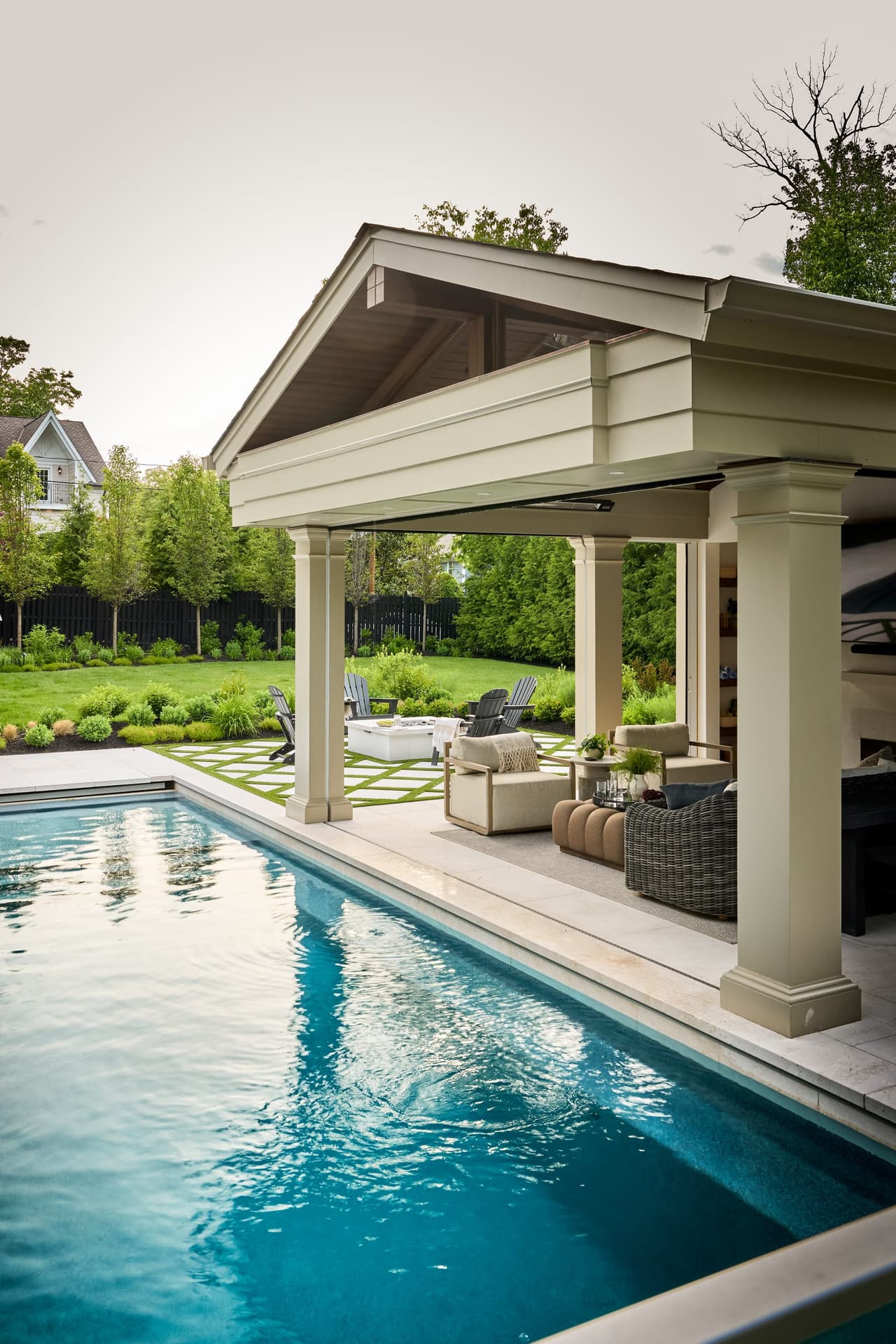 Gabled pool pavilion with detailed columns and an open-air lounge above a limestone pool surround in Westfield, NJ, built by Michael Robert Construction
