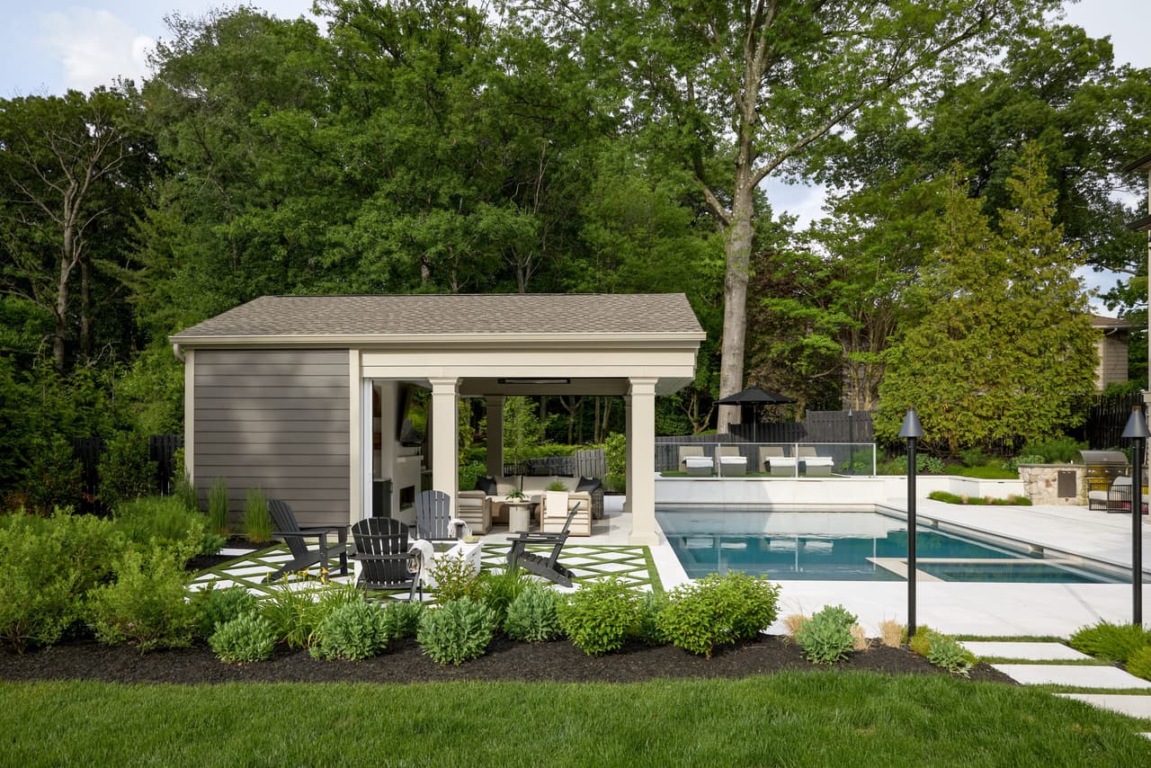 Gabled pool pavilion with columned openings and an open-air lounge beside the pool of a Westfield, NJ home built by Michael Robert Construction
