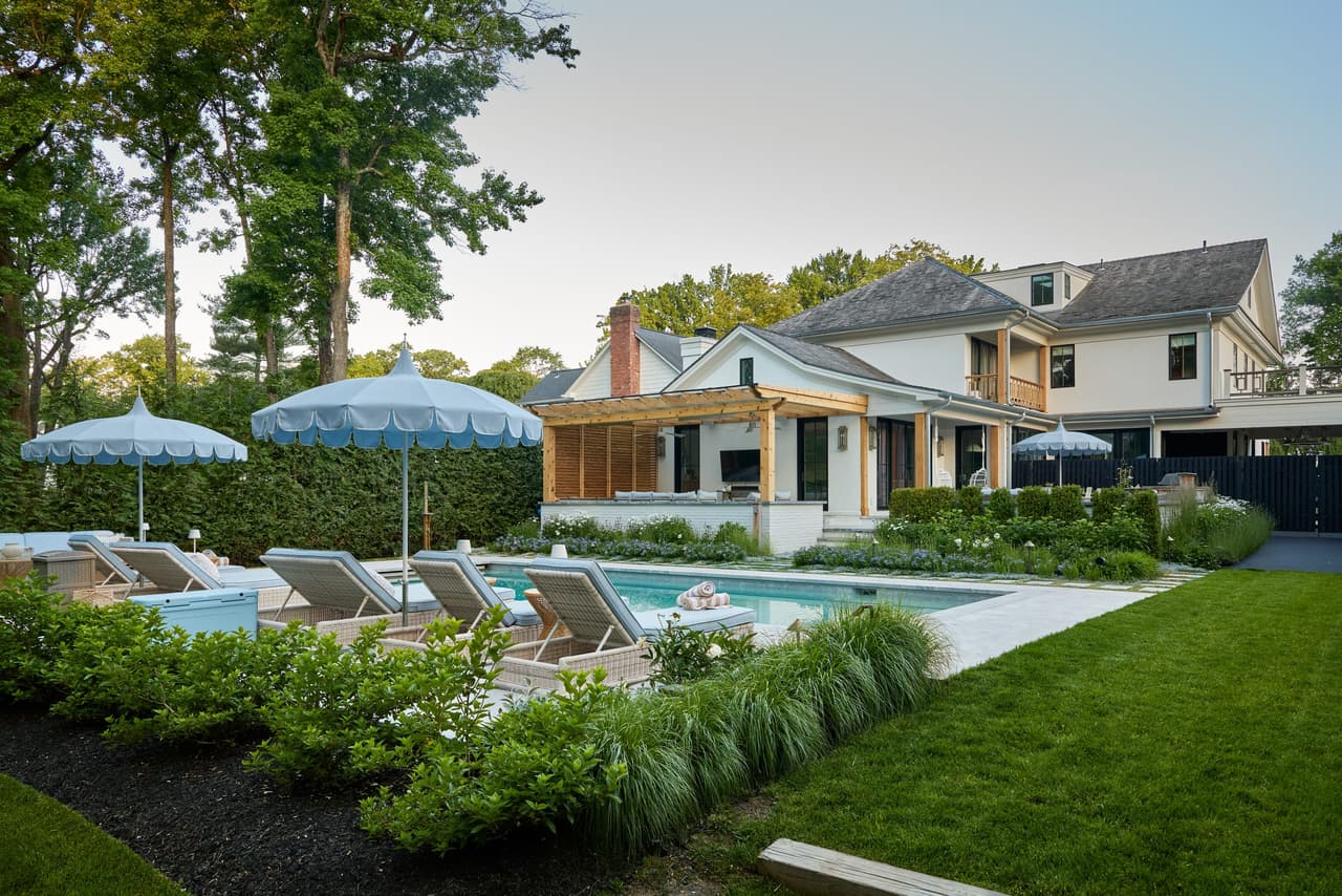 Backyard of a Westfield, NJ home with a pool, scalloped umbrellas, a cedar pergola and a stone patio, built by Michael Robert Construction