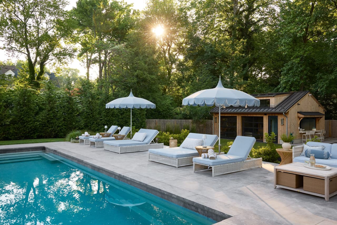 Pool, loungers and the cedar pool house in the backyard of a Westfield, NJ new-construction home, in late afternoon light