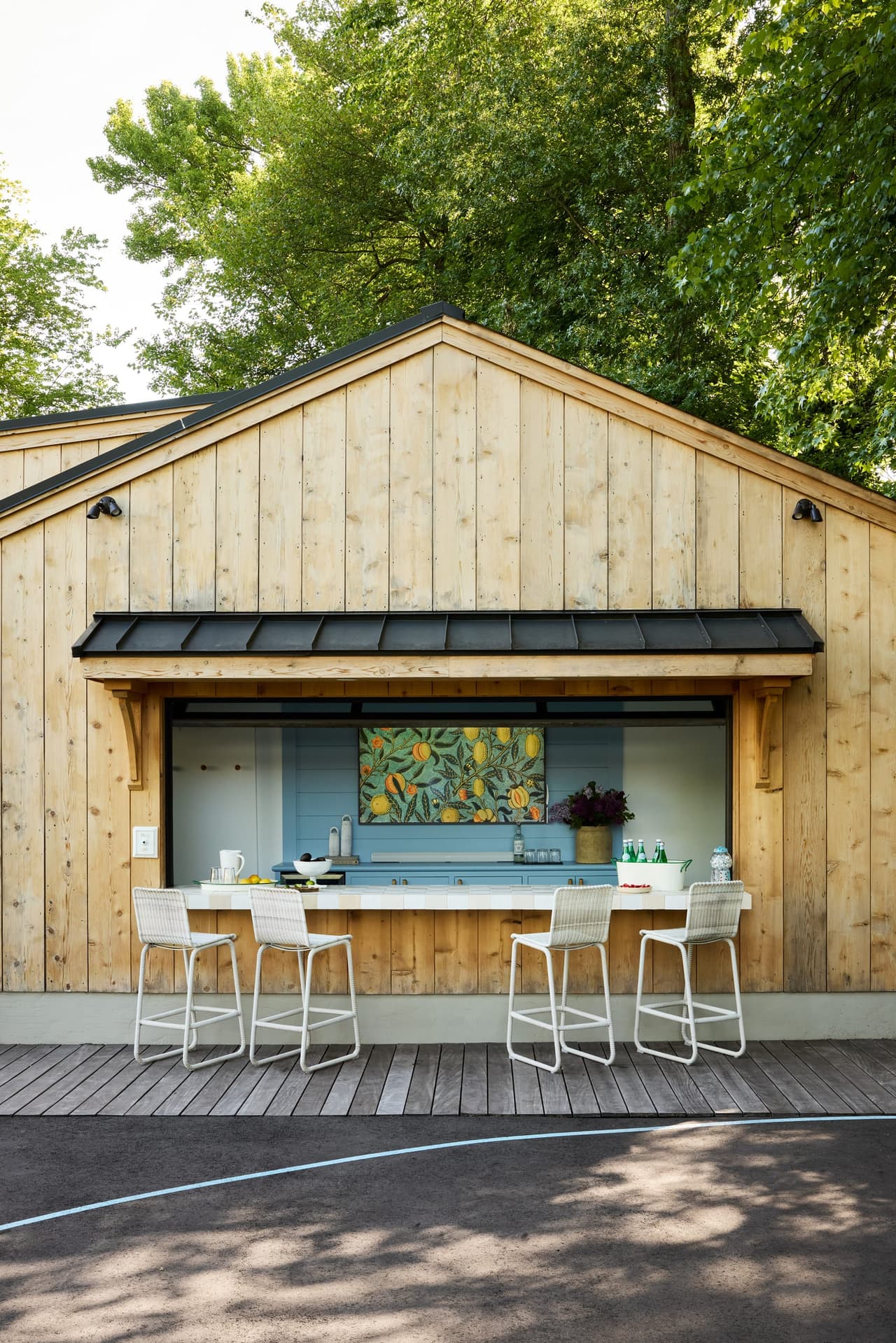 Cedar-clad pool house in Westfield, NJ with a pass-through bar, light blue cabinetry and counter stools on the deck, built by Michael Robert Construction
