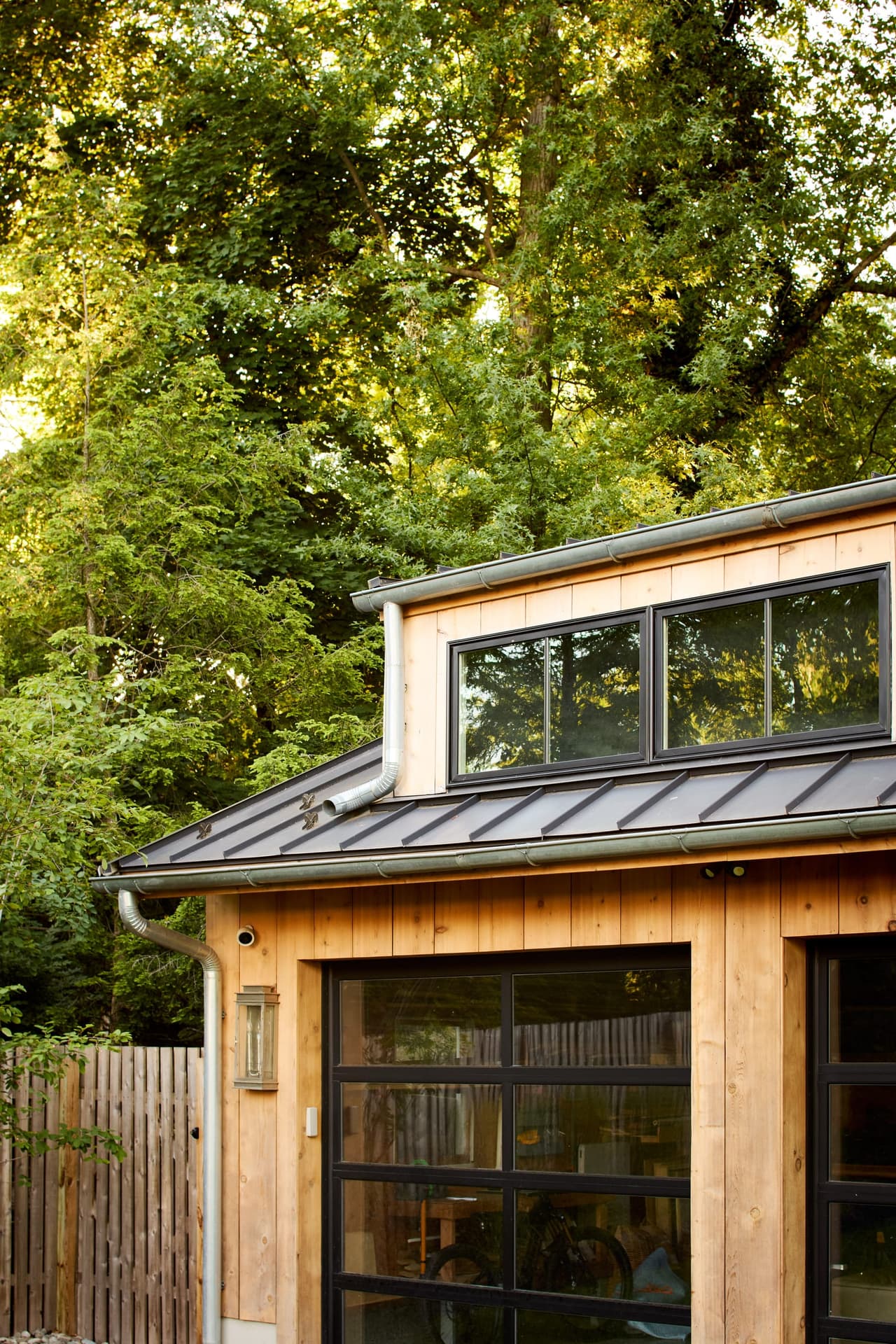 Cedar siding meeting the standing-seam metal roof and clerestory glazing of a custom pool house in Westfield, NJ