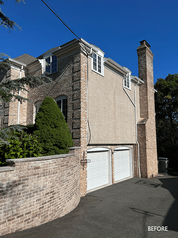The side of the existing home before renovation, in brick with a steep drive to the garage, in Mountainside, NJ
