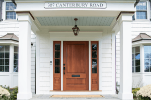 Cedar front door under a blue-painted porch ceiling at a Westfield, NJ exterior renovation, with a lantern overhead and hydrangeas either side of the step