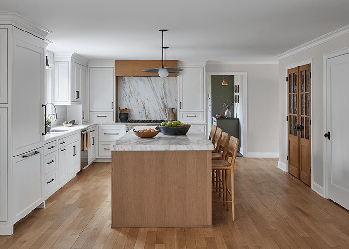 Kitchen of a Westfield, NJ home renovation with white cabinetry, a white oak island and a marble slab run up behind the range